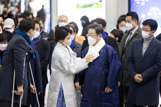 지난 1월31일 이재명 더불어민주당 대선후보의 부인인 김혜경씨가 서울 용산역에서 귀성객들에게 새해 인사를 하던 중 이 후보의 옷매무새를 챙기고 있다. 더불어민주당 선거대책위원회 제공·연합뉴스
